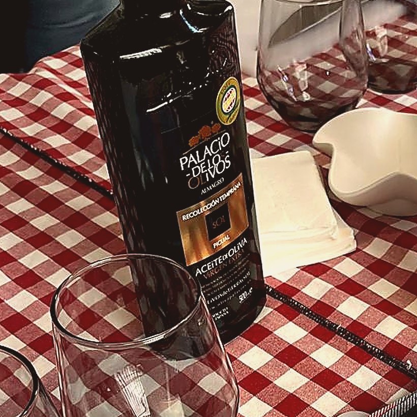 Botella de aceite de oliva virgen extra premiado sobre mantel de cuadros