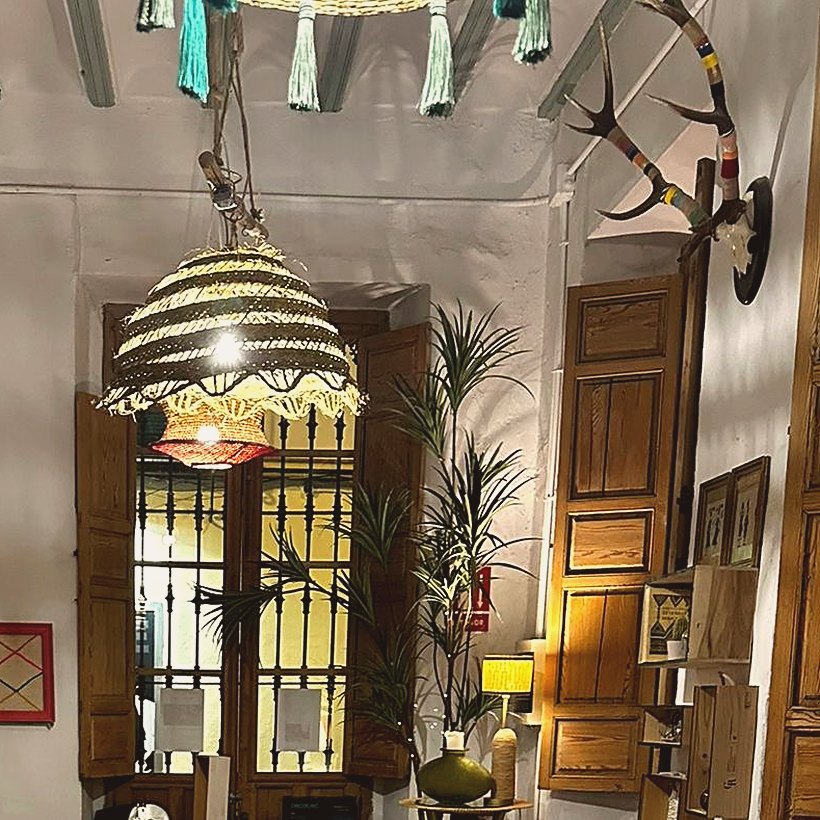 Sala andaluza con vigas, lámpara de mimbre y ventanal con rejería