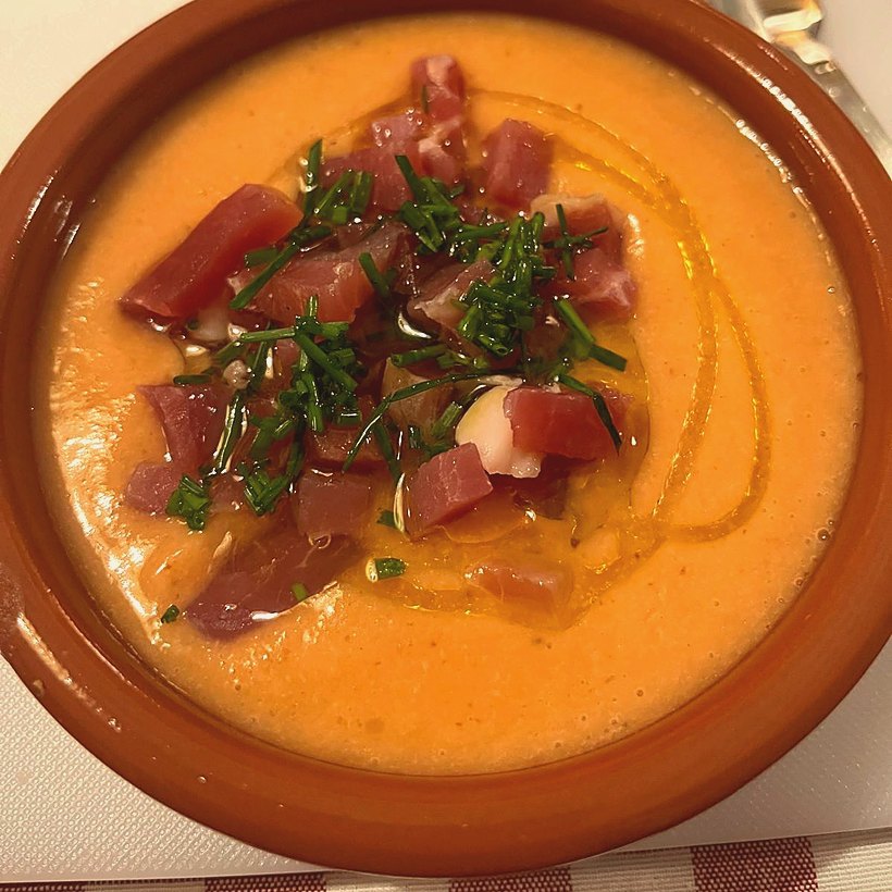 Tapa servida en cazuela de barro, con jamón, hierbas y un hilo de aceite